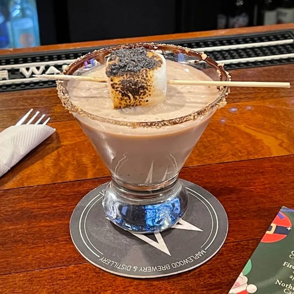 A chocolate martini with a toasted marshmallow garnish on a wooden bar at Pub 47.